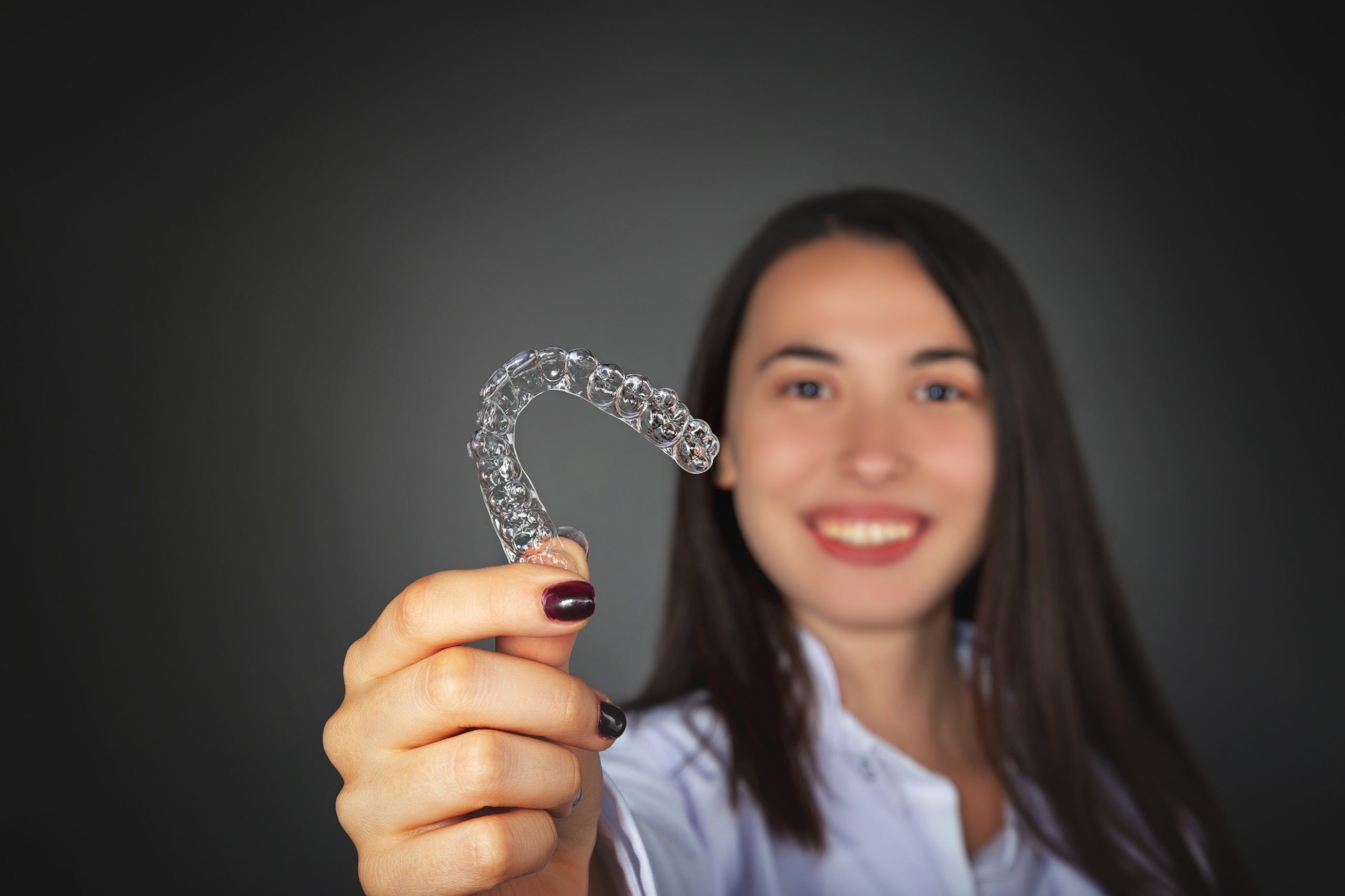 Woman holding aligner for Invisalign in Allen